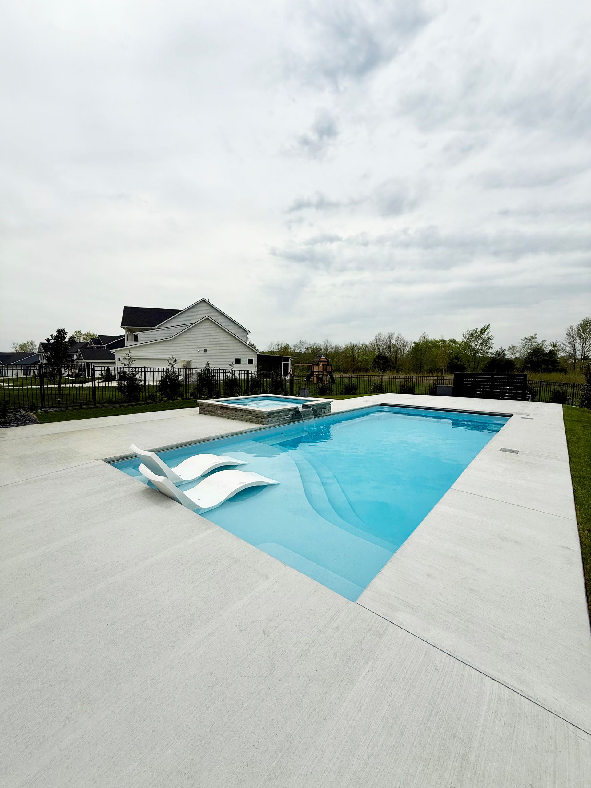 Close-up of spa water cascading into the Aspen pool, creating a peaceful backyard retreat.