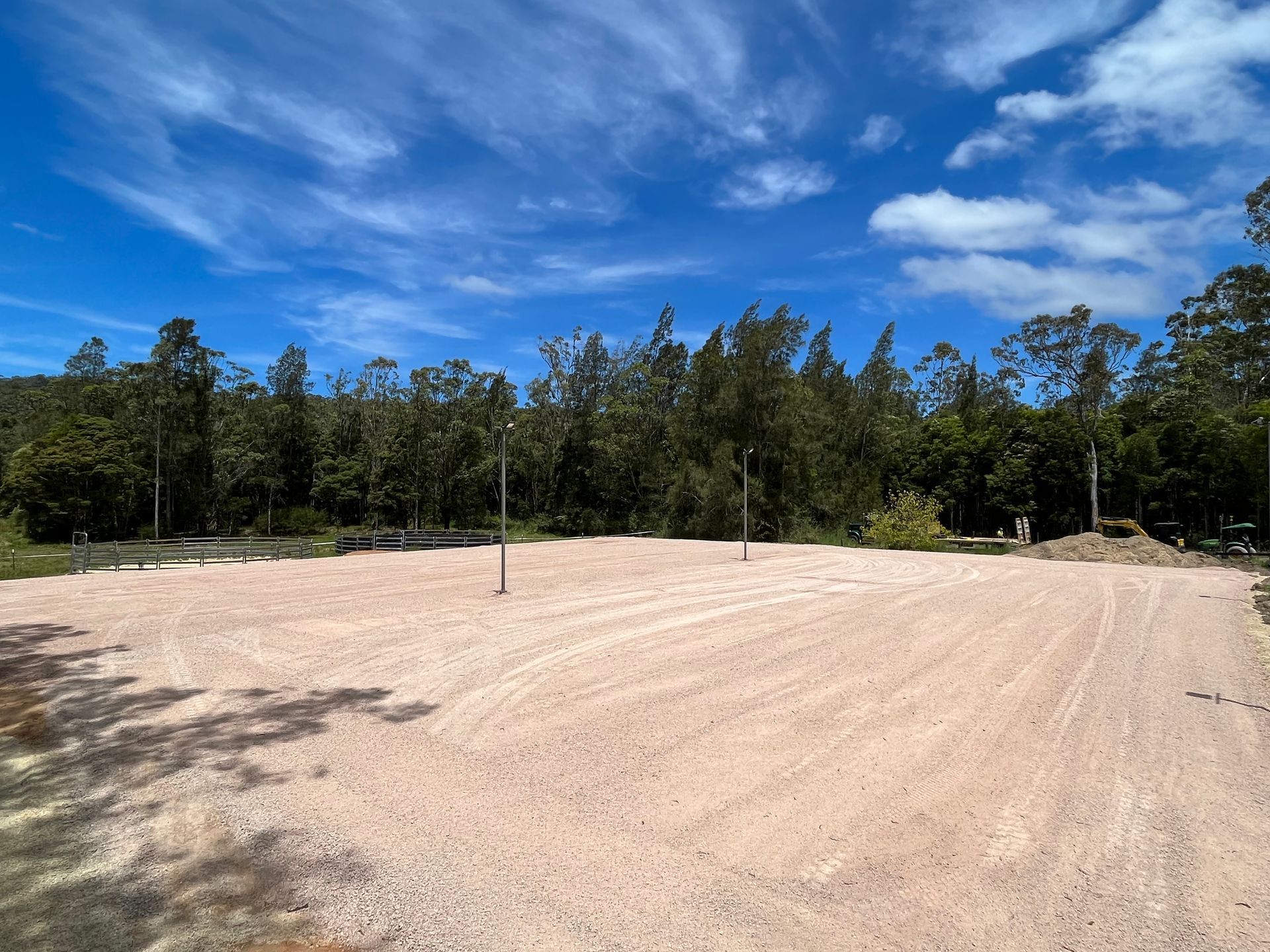 Gravel lot cleared with poles, trees in the background, under blue sky with clouds — Azza's Mini Diggers in Port Macquarie, NSW