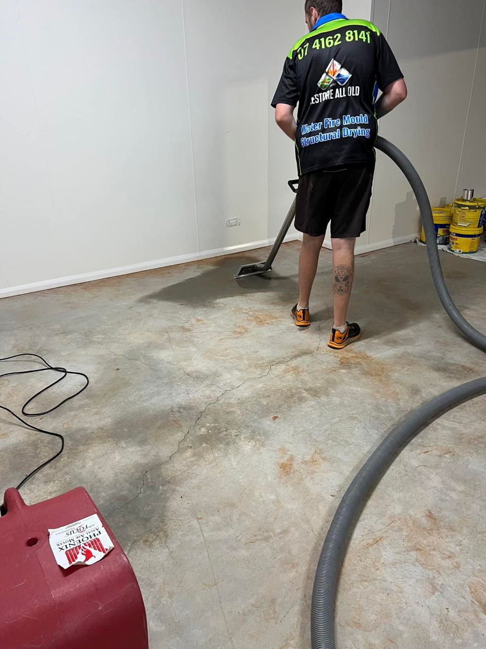 A Man is Cleaning a Concrete Floor — Restore All Qld in Bundaberg, QLD