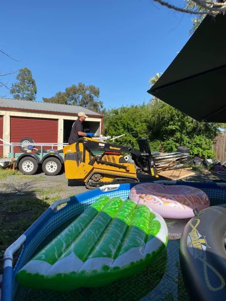 A Man is Driving a Bulldozer Next to the Garage Door — Restore All Qld in Kingaroy, QLD