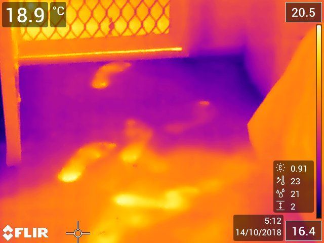 Thermal camera view of footprints on a floor, showing warmer areas in orange and cooler areas in purple.