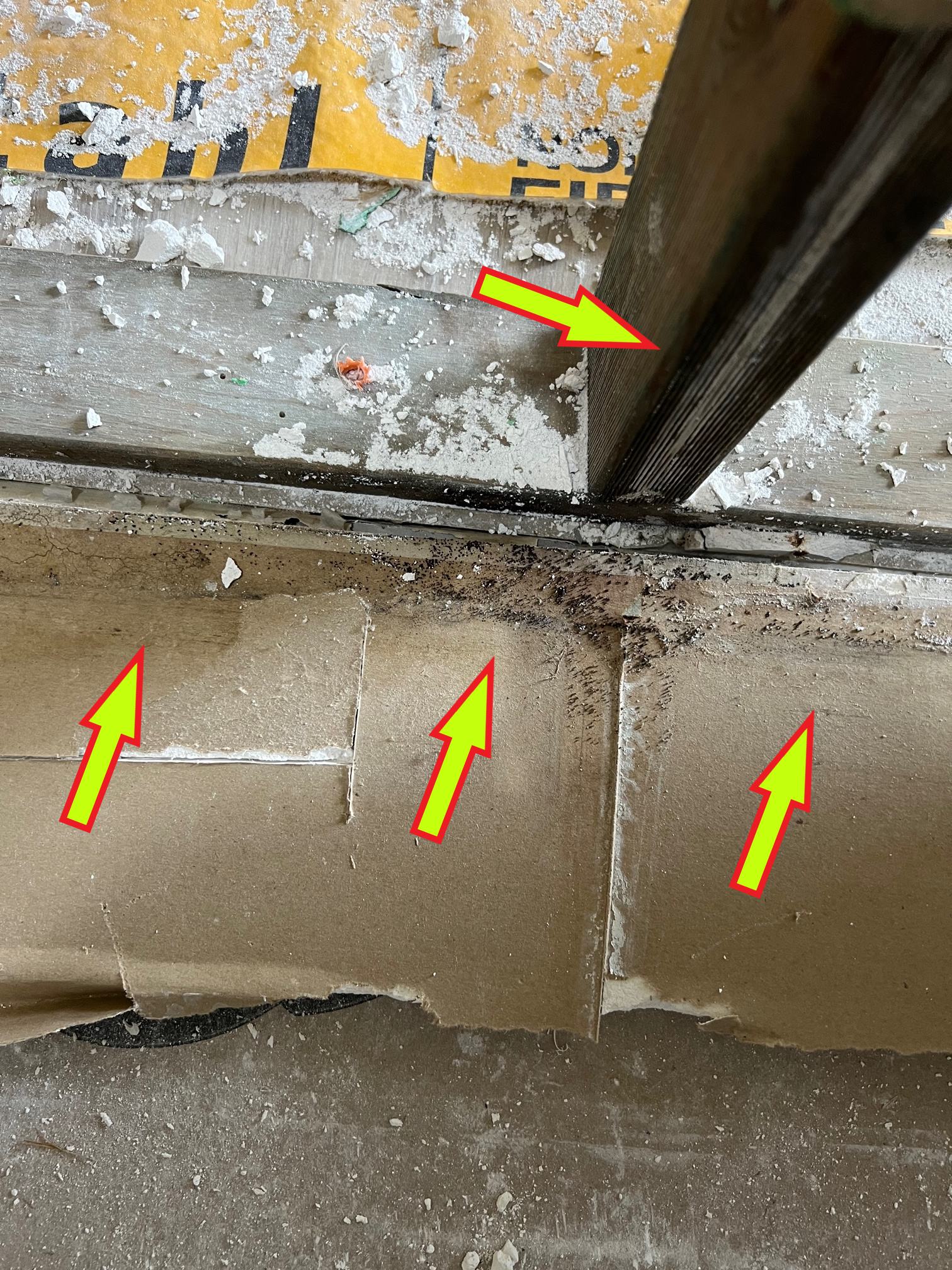 Close-up of a construction site showing a wooden beam and drywall with indications of potential mold growth.