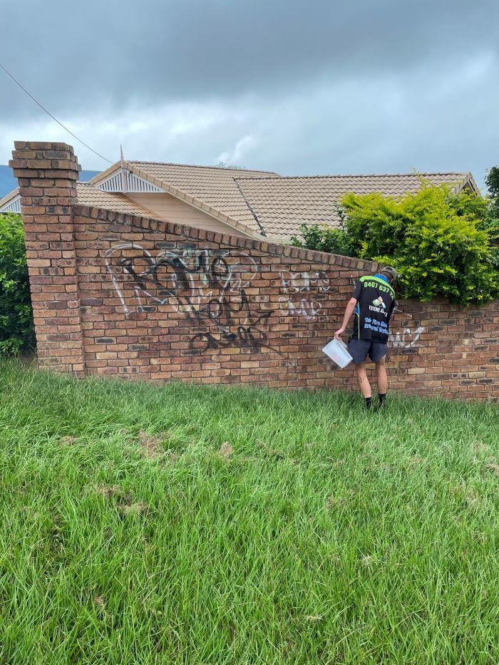 A Man is Removing the  Graffiti on the Brick Wall — Restore All Qld in Kingaroy, QLD