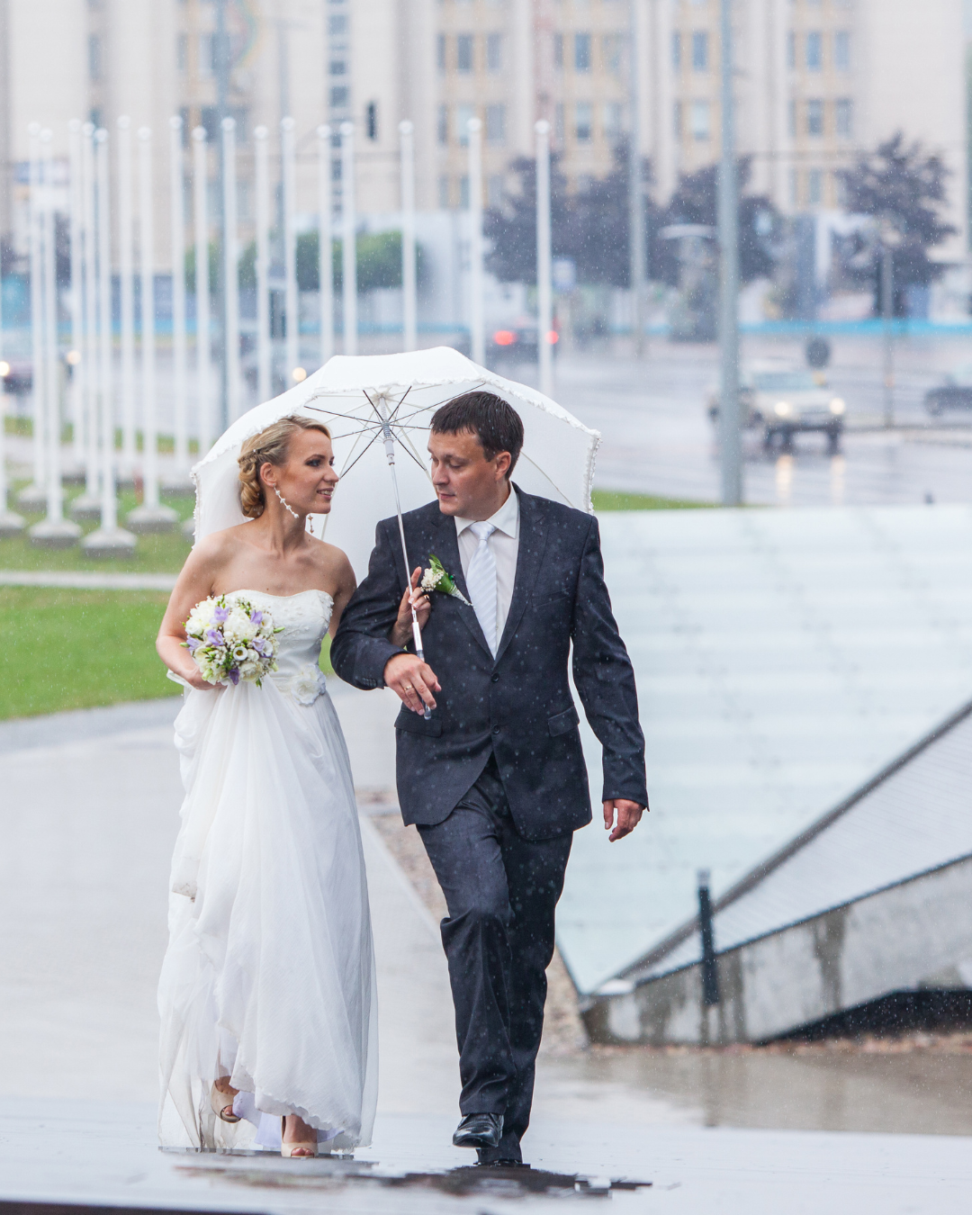 bride and groom with umbrella on their wedding day walking in the rain