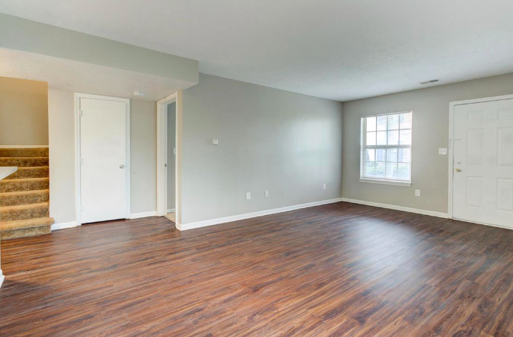 An empty living room with hardwood floors and stairs.