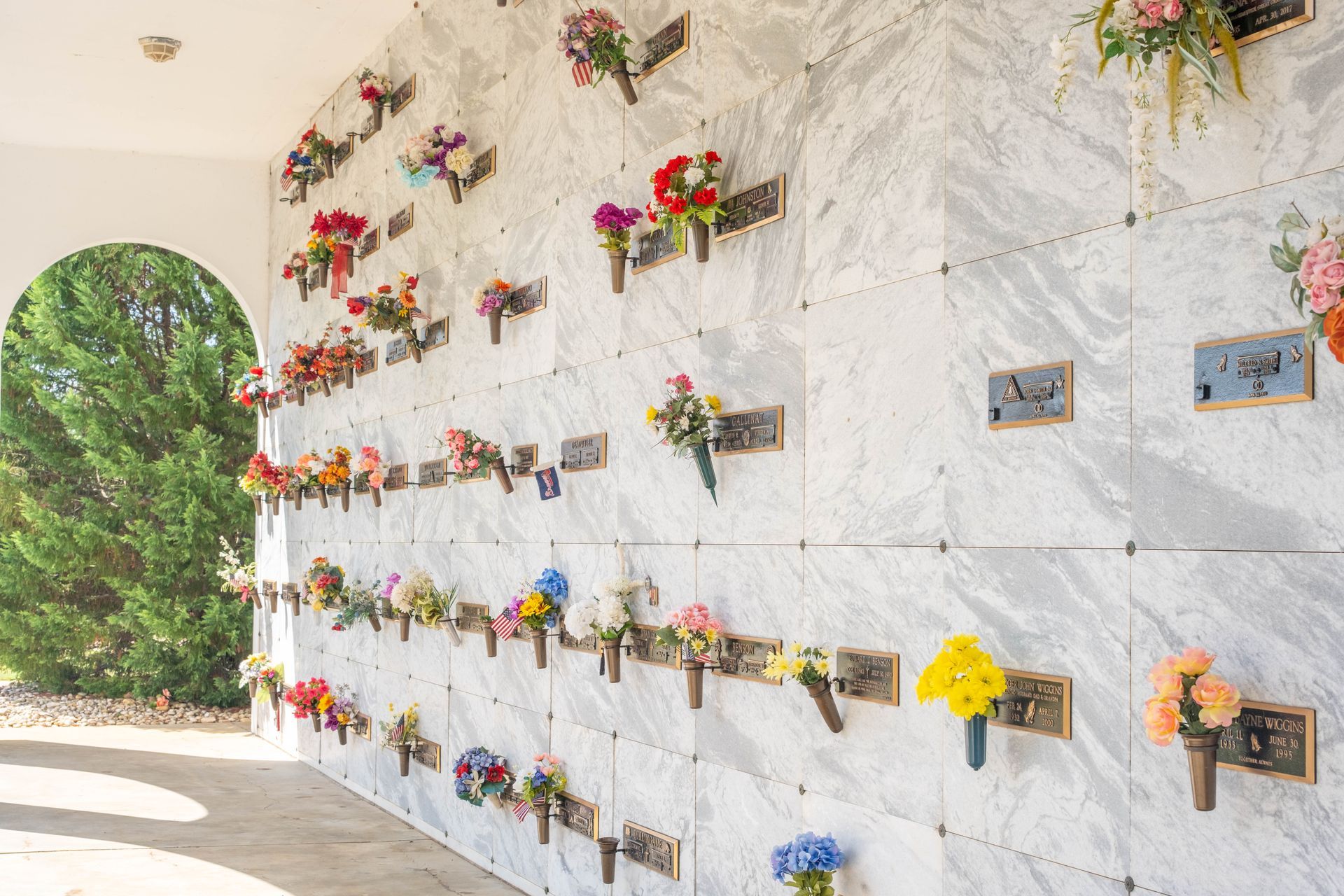 Wall of columbarium niches with flowers in a memorial garden.