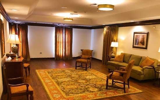 Empty waiting room with plush seating, oriental rug, wood accents, and window curtains.