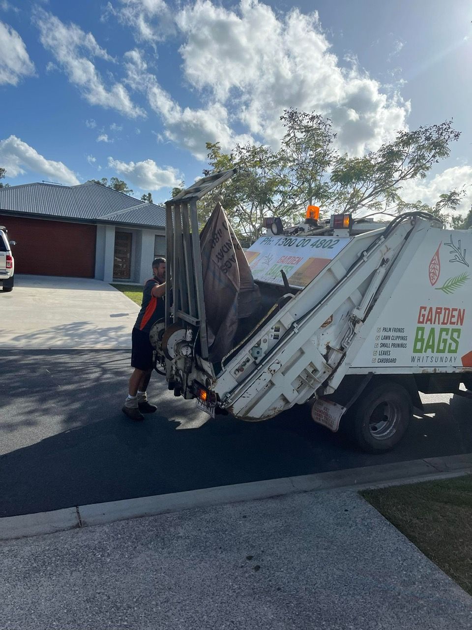 A Rubbish Truck Is Parked On The Side Of The Road In Front Of A House — Garden Bag in Kelsey Creek, QLD