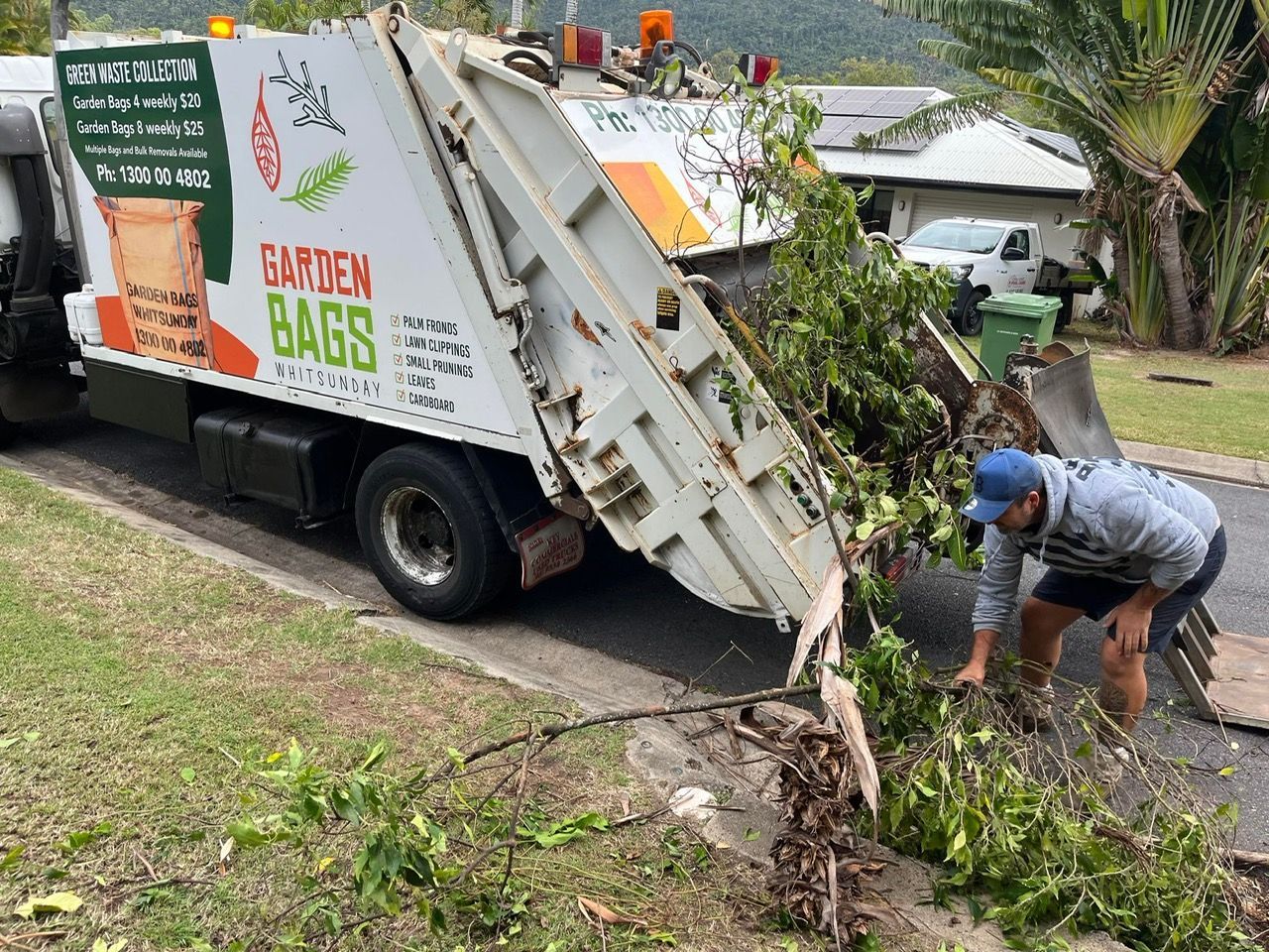 A Man Is Picking Up Branches From A Rubbish Truck — Garden Bag in Kelsey Creek, QLD