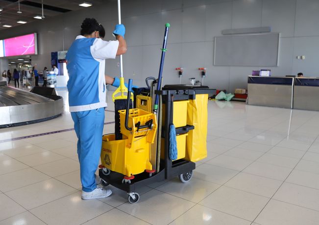 A man is cleaning the floor of an airport with a mop.