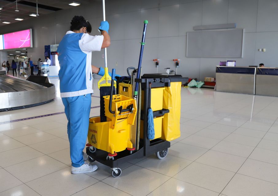 A man is cleaning the floor of an airport with a mop.