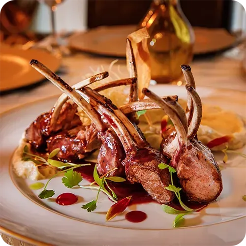 Um prato branco coberto com costeletas de cordeiro e molho sobre uma mesa.
