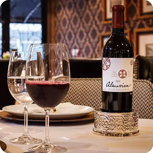 Uma garrafa de vinho está sobre uma mesa ao lado de duas taças de vinho.