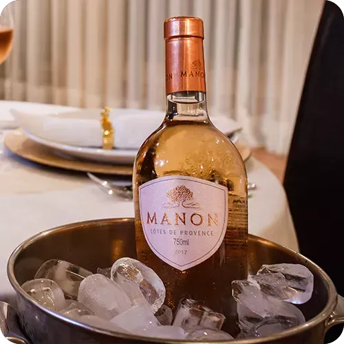 Uma garrafa de vinho da mansão está em um balde de gelo.