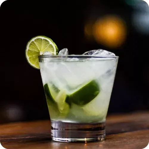 Um close de uma bebida com gelo e limão sobre uma mesa.