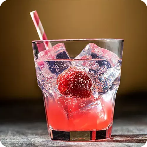 Um copo de líquido rosa com cubos de gelo e um morango.