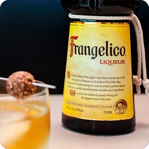 Uma garrafa de licor frangelico está ao lado de um copo com líquido.