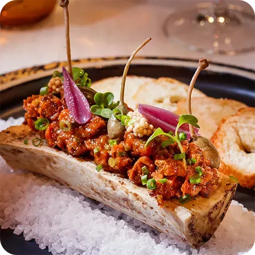 Um grande osso cheio de carne e legumes num prato.