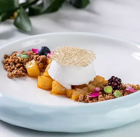 Um prato branco coberto com sobremesa e frutas sobre uma mesa.