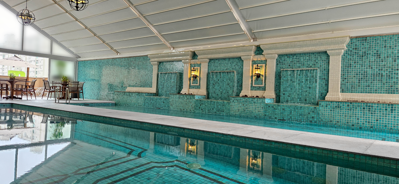 Grande piscina interior com parede e tecto em azulejos.