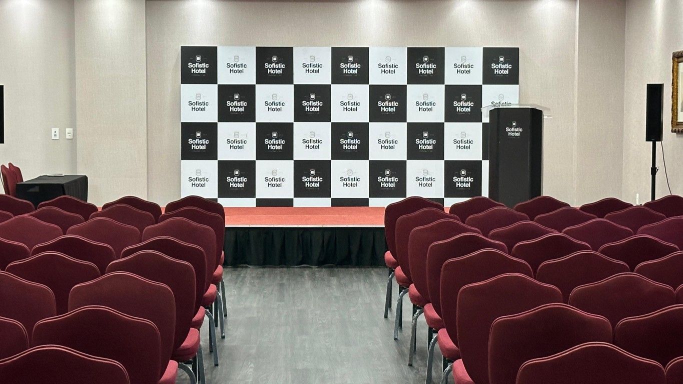 Uma grande sala com cadeiras vermelhas e uma tela de projetor