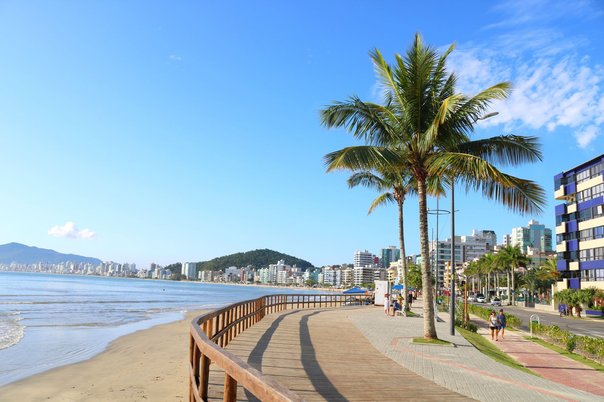 Uma praia com palmeiras e edifícios ao fundo