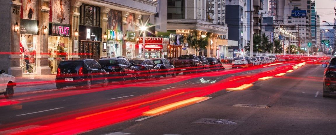 Uma foto de longa exposição de uma rua da cidade à noite com carros passando por ela.