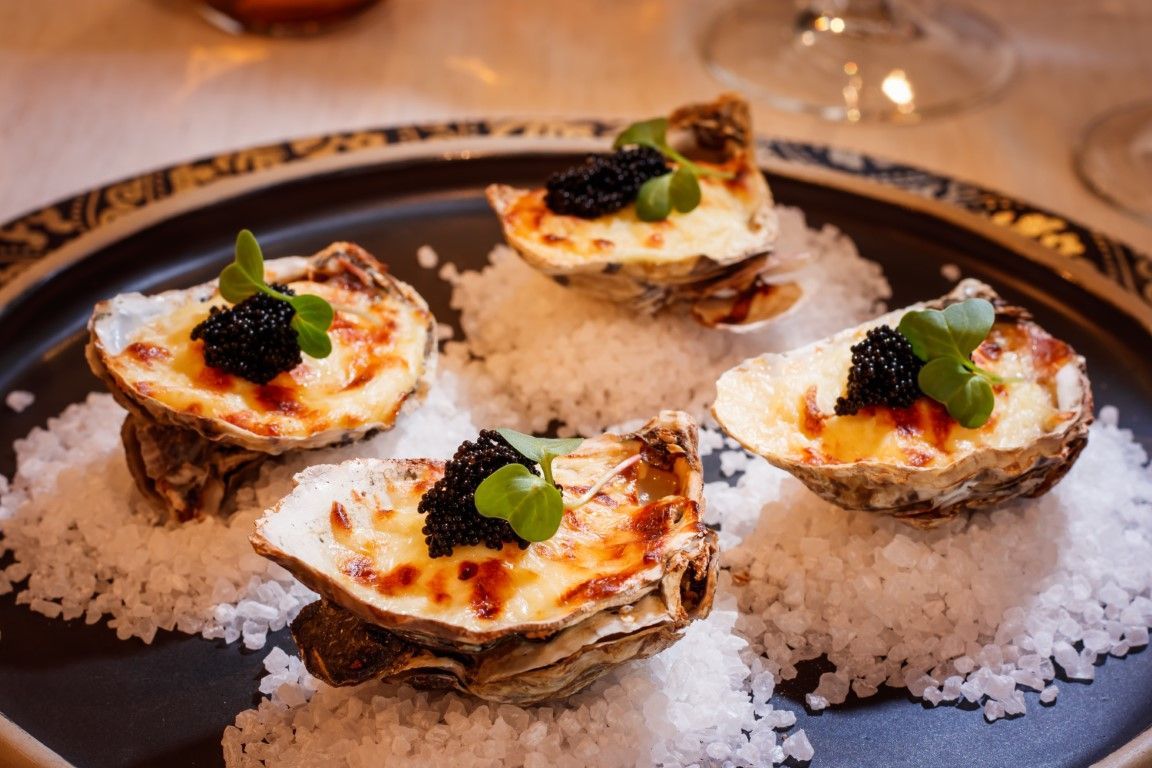Um close de um prato de comida com ostras e caviar sobre uma mesa.
