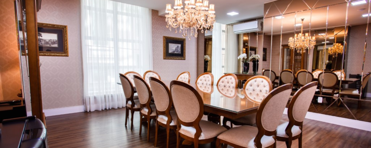 Uma grande sala de jantar com uma longa mesa e cadeiras e um lustre.