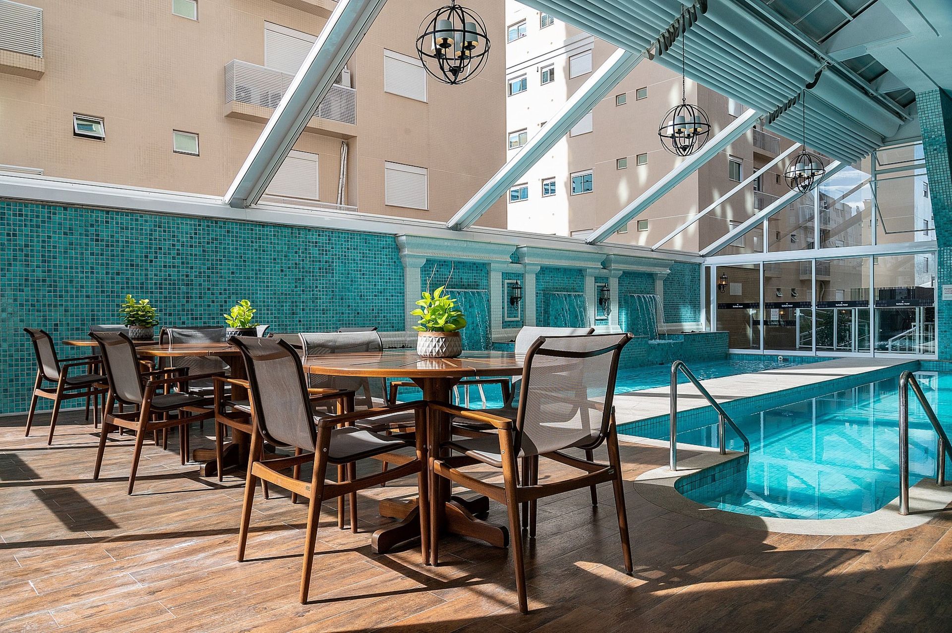 Uma piscina com mesas e cadeiras em frente.