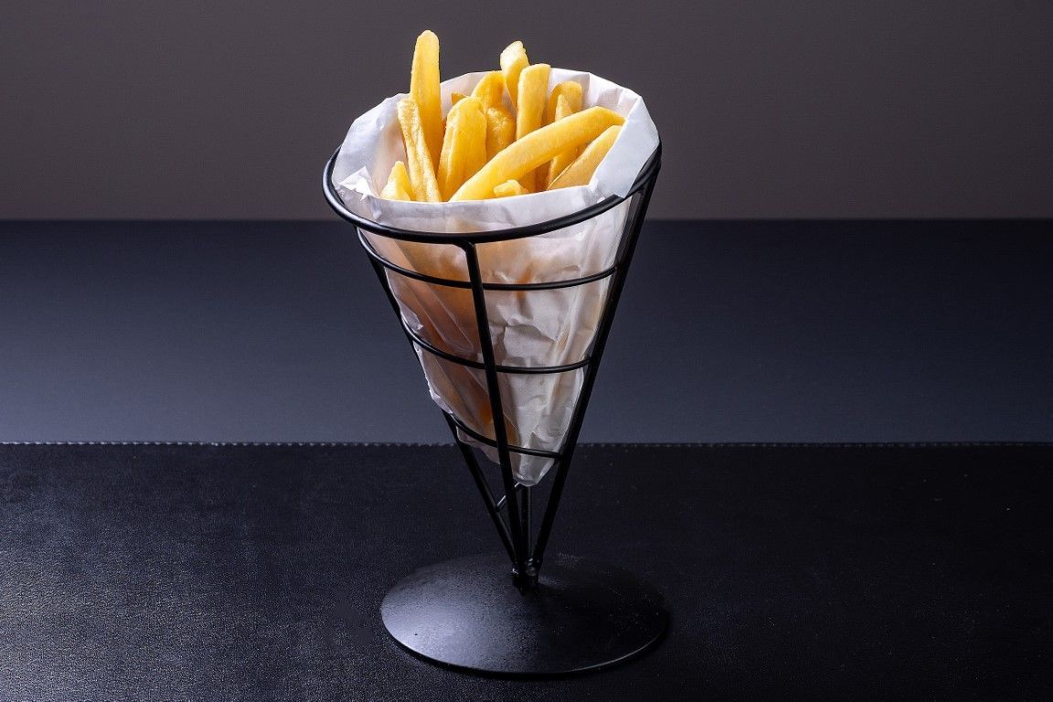 Uma cesta cheia de batatas fritas está sobre uma mesa.