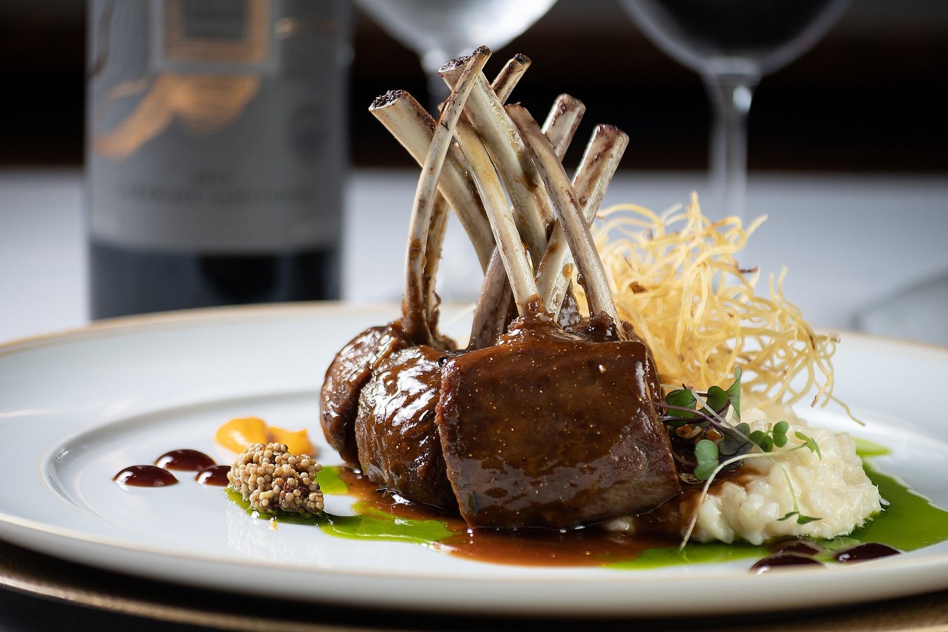 Um prato branco coberto com costeletas de cordeiro e purê de batata