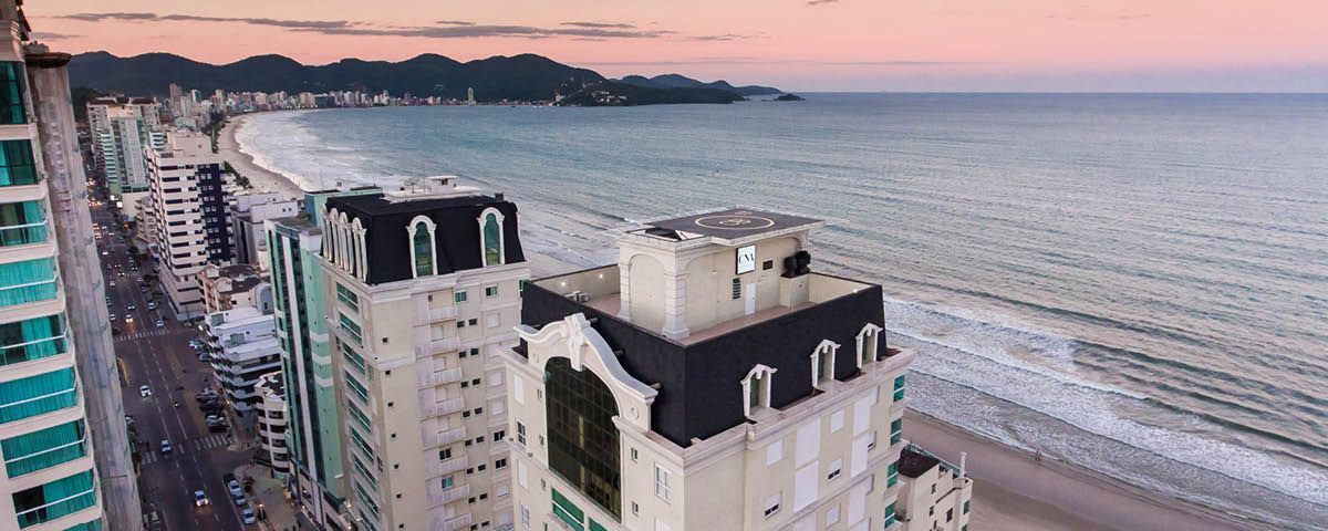 Uma vista aérea de uma cidade perto do oceano com um grande edifício em primeiro plano.