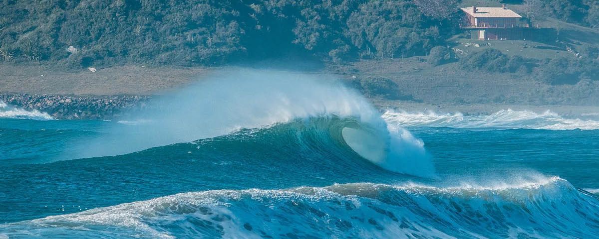 Uma grande onda está quebrando na costa de uma praia.