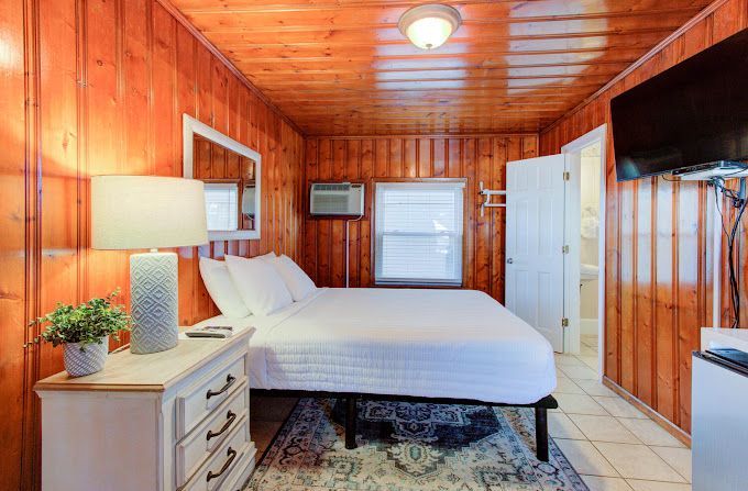 A bedroom with a bed , nightstand , lamp and television.