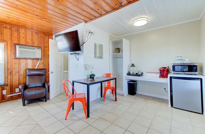 A living room with a table , chairs , microwave and television.