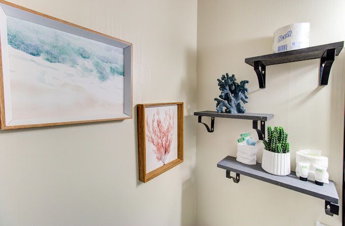 A bathroom with three shelves and a picture on the wall.
