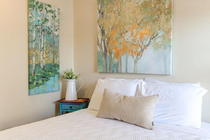 There are two paintings on the wall above the bed.