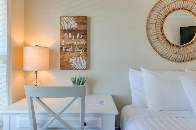 A bedroom with a bed , desk , lamp and mirror.