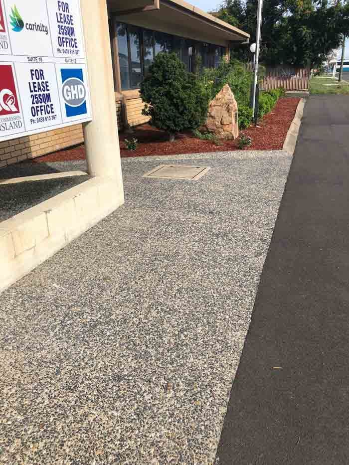 A Gravel Walkway Leads Past a Building with A Garden Bed — Wieland Concreting in Rockhampton, QLD