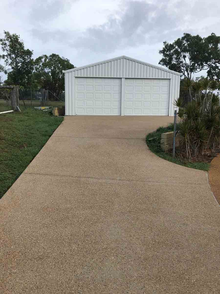 Driveway Leading to A White Metal Garage with Two Doors — Wieland Concreting in Rockhampton, QLD