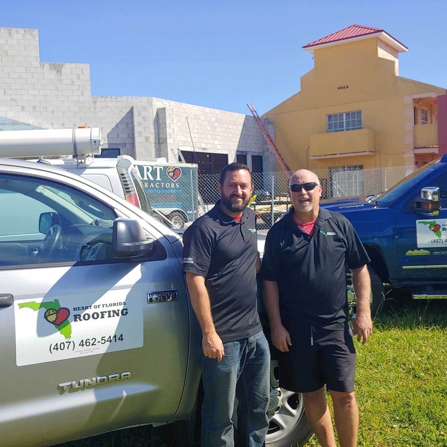 Two men standing next to a truck that says roofing