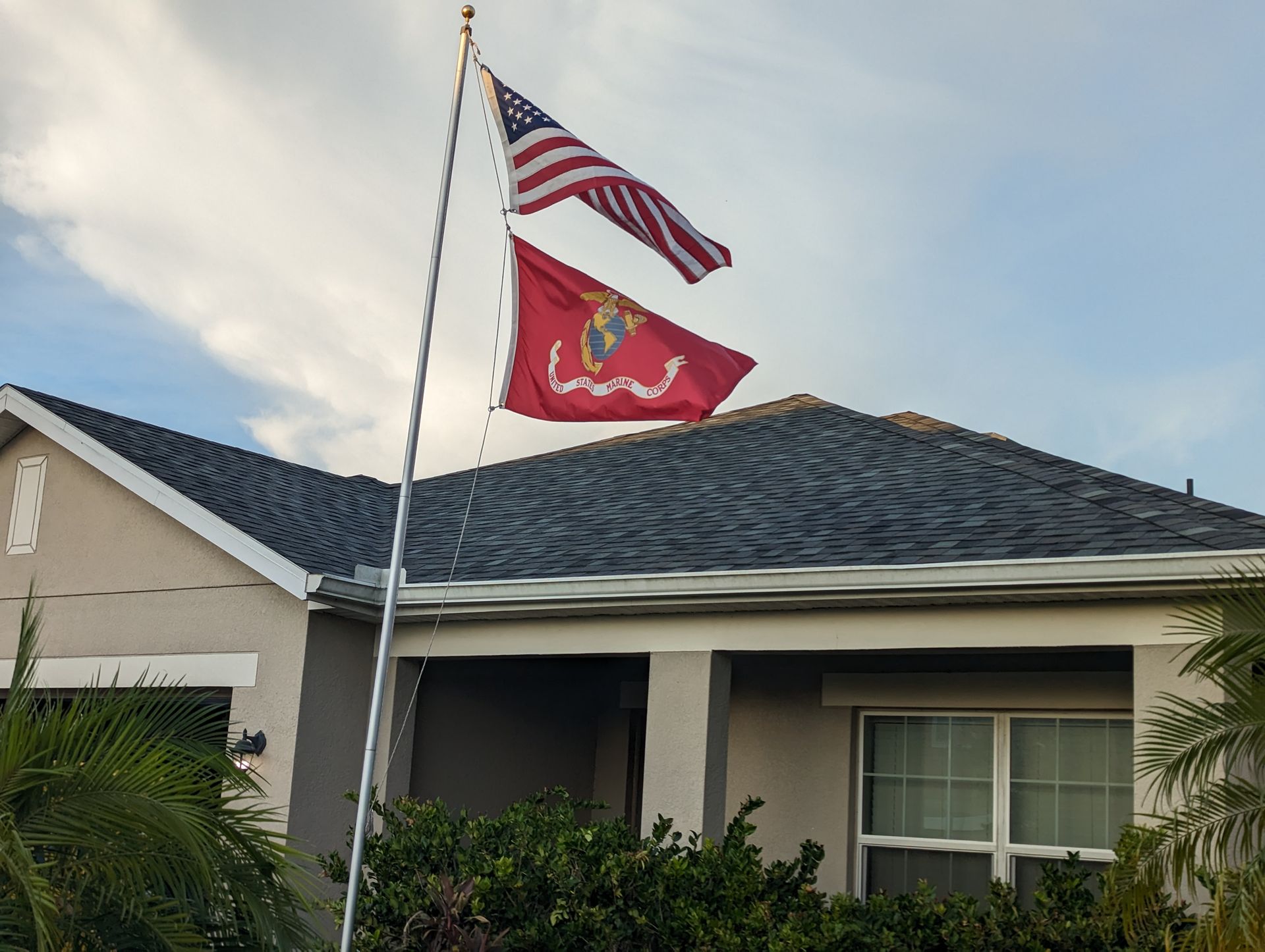 Two flags are flying in front of a house