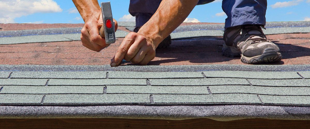 A man is installing shingles on a roof.
