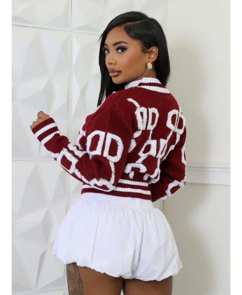 A woman is wearing a maroon sweater and white shorts.