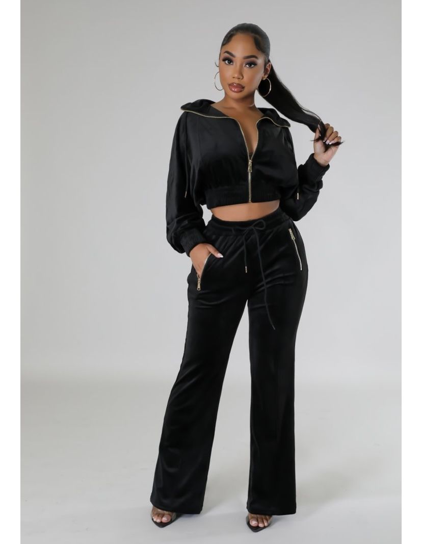 A woman is wearing a black crop top and wide leg pants