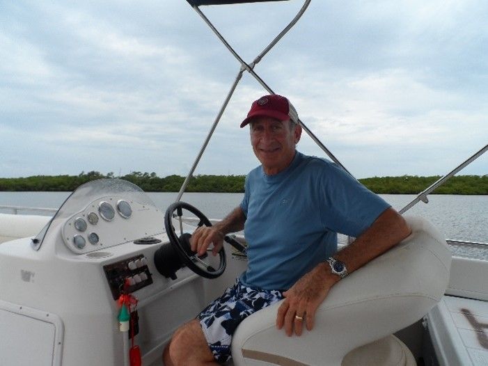 A man in a red hat is sitting in the cockpit of a boat