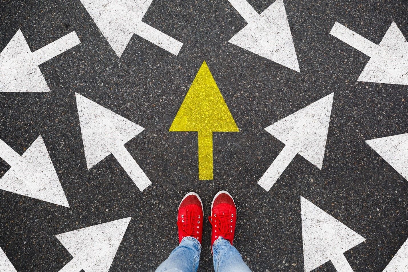 A person is standing in the middle of a road with arrows painted on it.