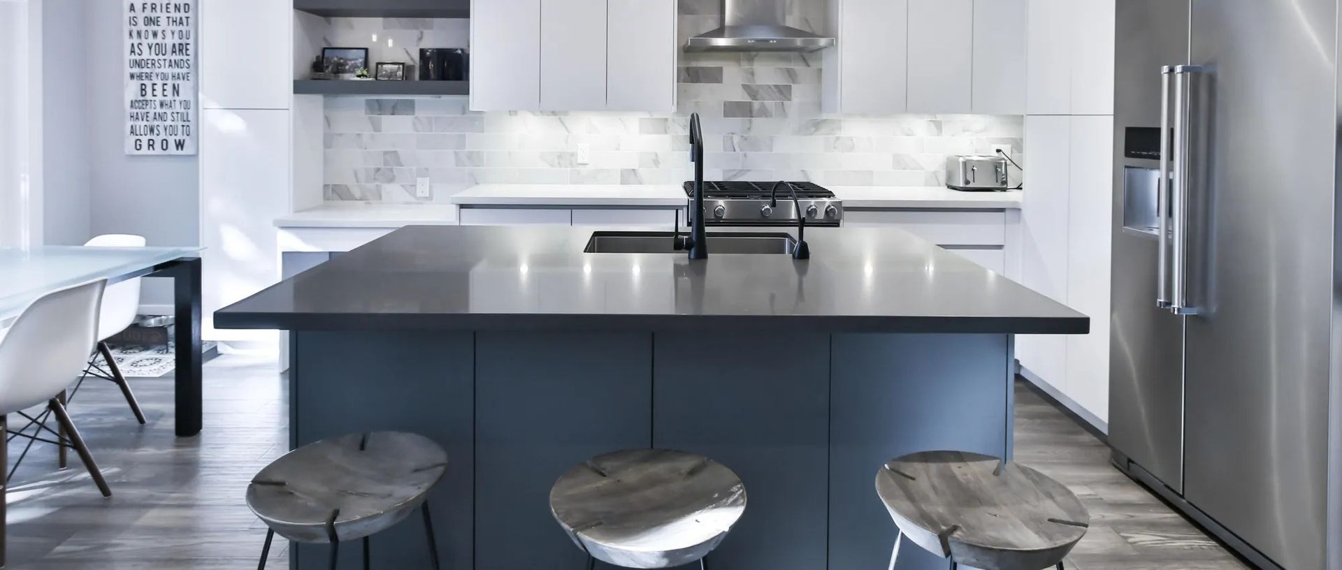 Modern kitchen with blue island, stools, stainless steel appliances, and white cabinets.