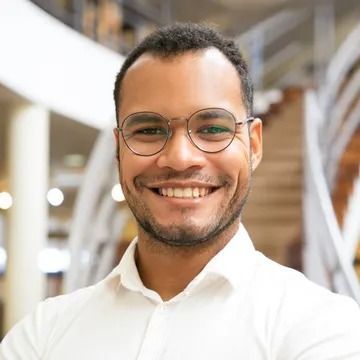 Man wearing glasses smiles broadly; soft focus background.